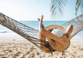 Egy személy, aki egy függőágyban fekszik a tengerparton.