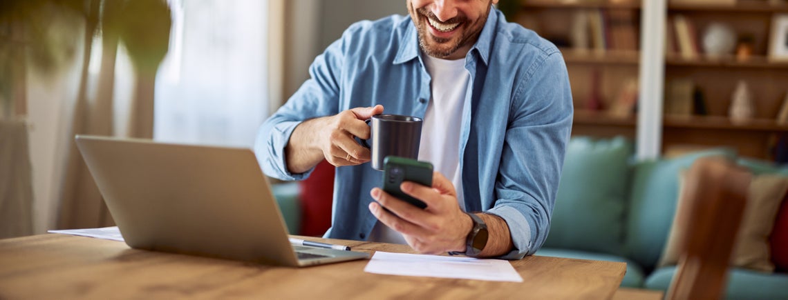 Muž držiaci telefón a hrnček