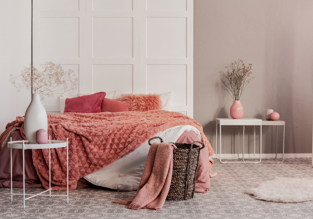 Egy ágy rózsaszín takaróval és kosárral egy szobában