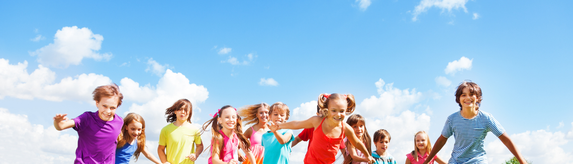 dzieci w wieku szkolnym, uczniowie podstawówki biegają i się cieszą, zdjęcie na tle błękitnego nieba