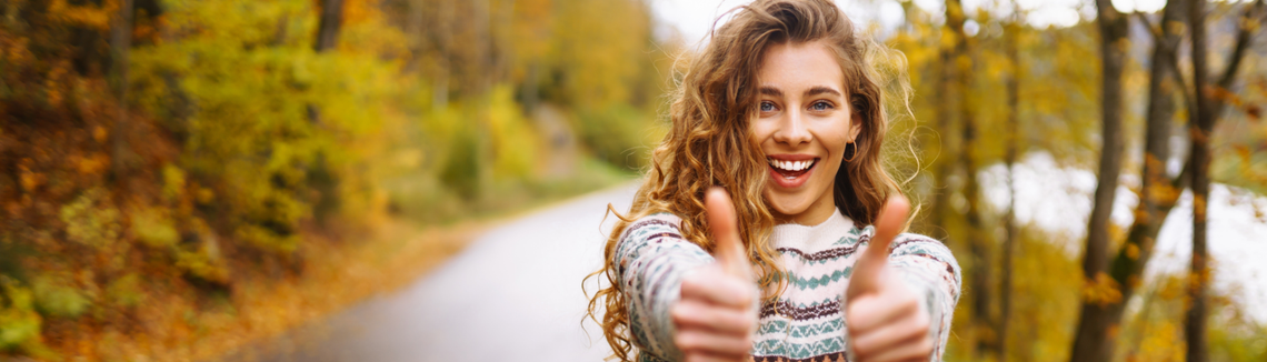 Egy nő mosolyog és felemeli a hüvelykujját