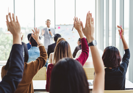 A group of people raising their hands in front of a whiteboard