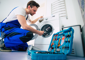 Muž opravuje práčku
