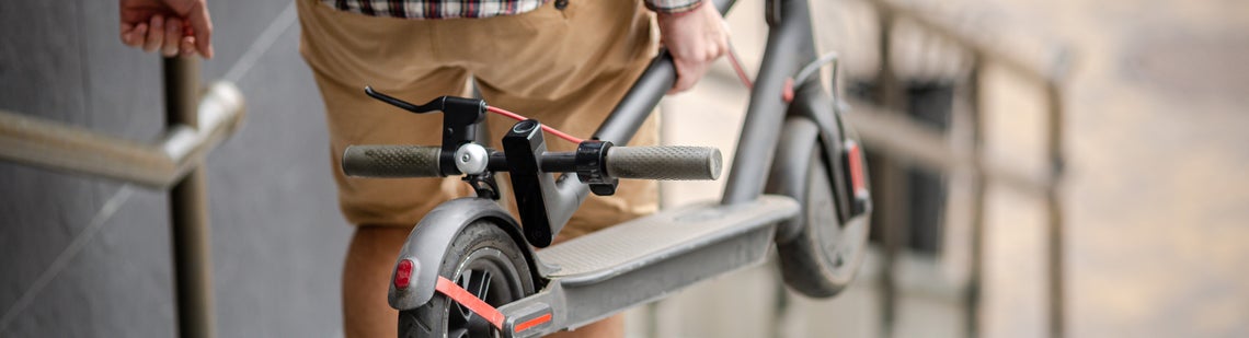 Човек, който държи скутер и слиза по стълби.