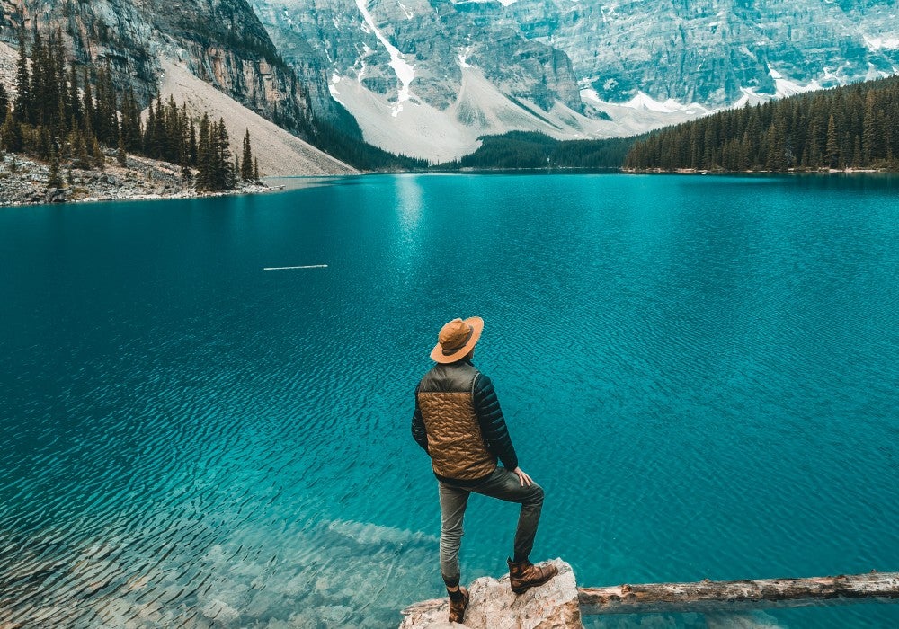 Muž stojaci na kmeni pri jazere