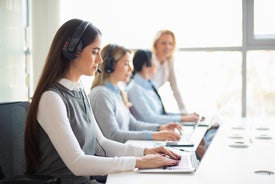 Egy csoport nő ül az asztaloknál, fejhallgatóval a fejhallgatójukon