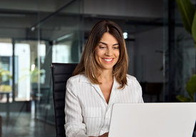 Egy nő ül egy széken, laptopot használ