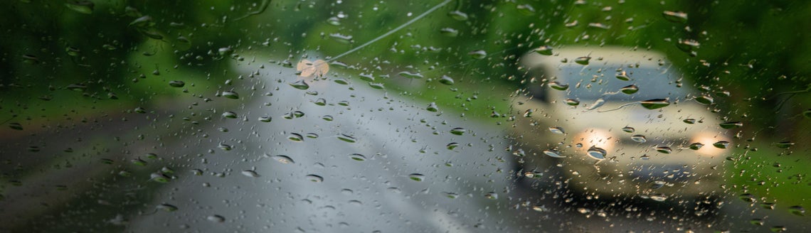 Auto jedoucí po silnici a na čelním skle se odrážejí kapky