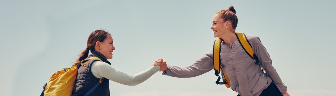 Dvě sportovkyně držící se za ruce a pomáhající si na skalách