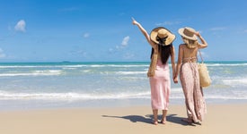 Dvě ženy stojící na pláži a hledící na oceán