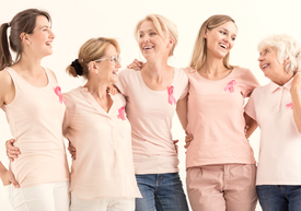 Egy csoport rózsaszín pólót viselő nő egymásba karolva