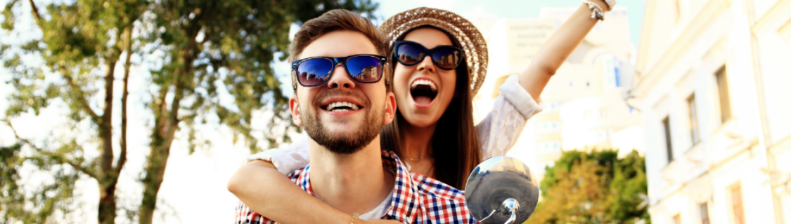 Un bărbat și o femeie care poartă ochelari de soare și zâmbesc