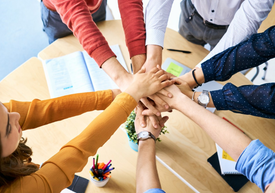 Събрани ръце в знак на обединение на екип над маса за срещи