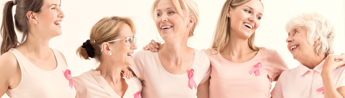 Egy csoport rózsaszín pólót viselő nő egymásba karolva