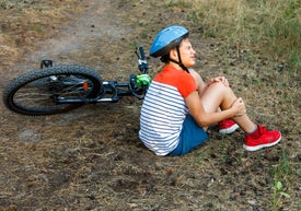 Chłopiec siedzący na ziemi ze swoim rowerem