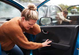 Žena otevírá kliku dveří auta