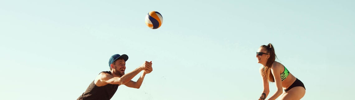 Muž a žena hrající plážový volejbal