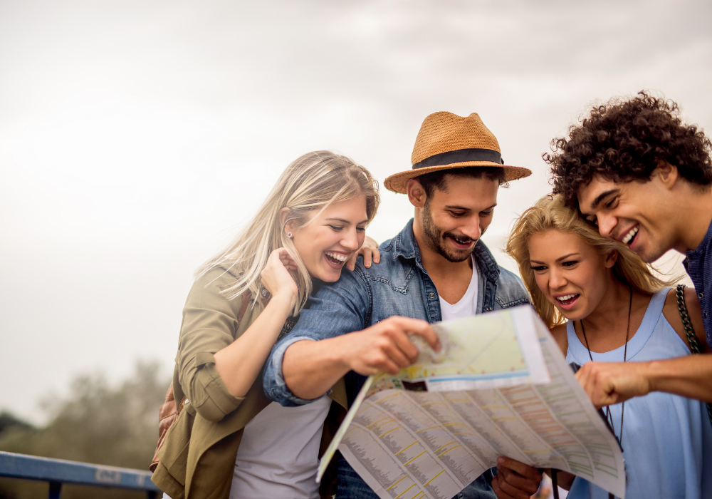 Група млади хора усмихнати разглеждат пътна карта.