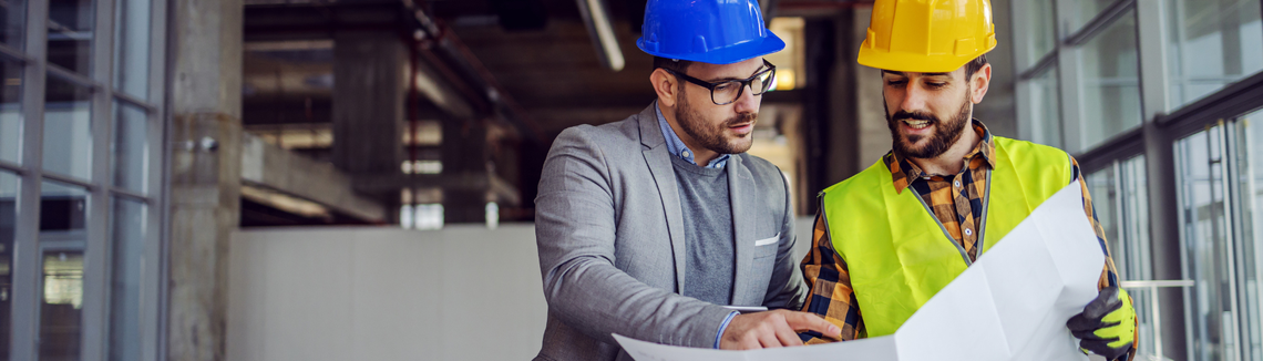 Egy férfi keménykalapot visel és egy papírlapot néz.