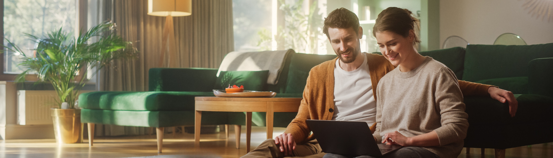 Egy nő és egy férfi ül a padlón egy laptoppal