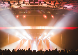 Вижда се публиката и осветена концертна сцена в зала.