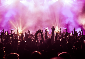 Emberek tömege a színpad előtt feltartott kezekkel.