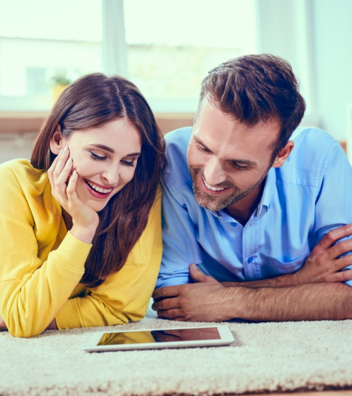 Egy férfi és egy nő a földön fekve, egy tabletet nézegetve