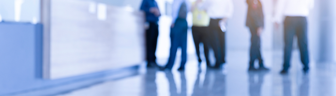 Elmosódott kép egy szobában álló emberekről.