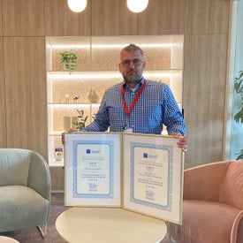 Egy férfi kezében kettő bekeretezett oklevél