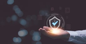 Ruka držiaca svietiaci štít s kontrolným znakom