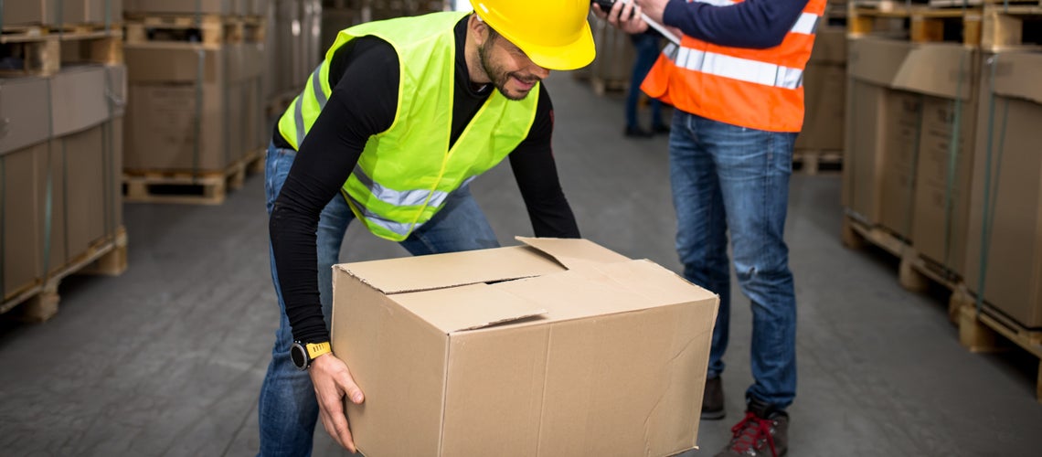 Muž v žltej šiltovke a veste drží škatuľu