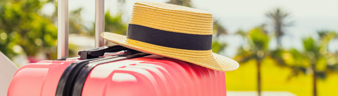 Egy kalapot és egy bőröndöt tartó kéz