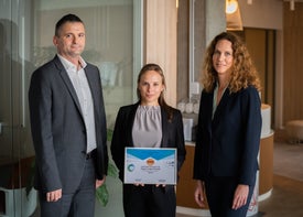 Emberek egy csoportja egy fal előtt állva oklevéllel