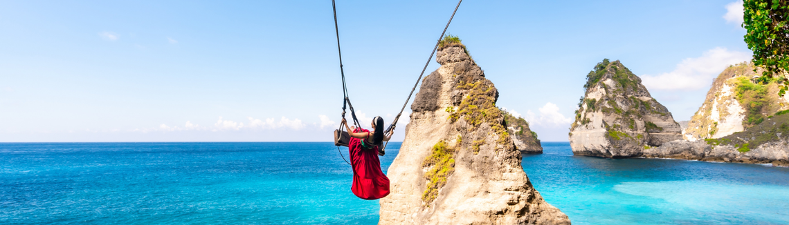 Egy nő hintázik egy szikla mellett a tenger fölött