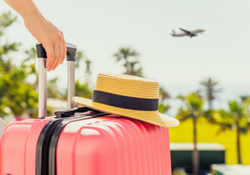 Egy kalapot és egy bőröndöt tartó kéz