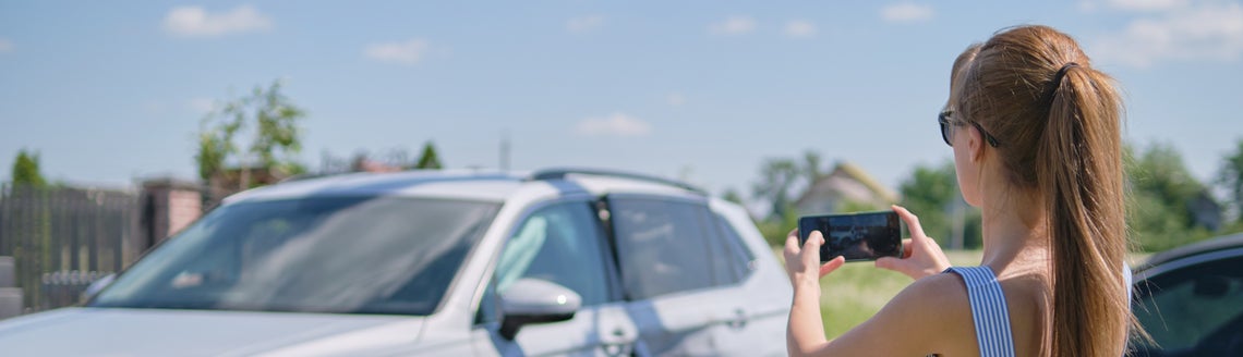 Žena fotí rozbité auto