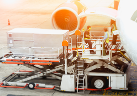 Машина за товарене на багаж издига към самолета голямо съоръжение.