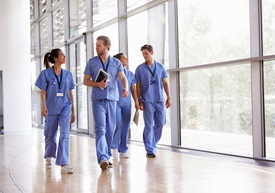 Un grup de persoane purtând halate albastre mergând pe un hol