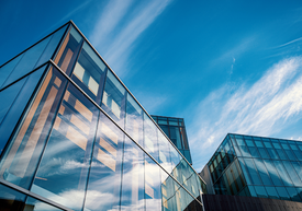 Egy üvegépület kék éggel és felhőkkel