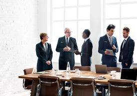 Skupina lidí v oblecích stojících kolem stolu