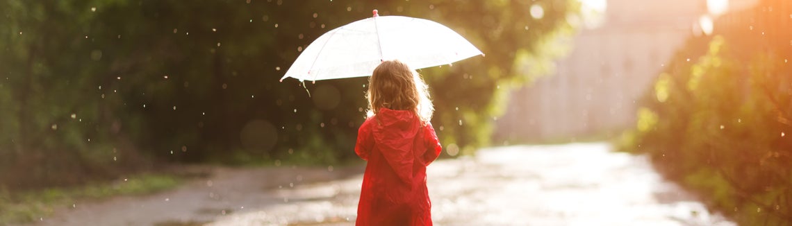 Dítě v červené pláštěnce s deštníkem v ruce