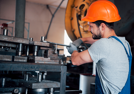 Muž s pracovní helmou pracující na stroji