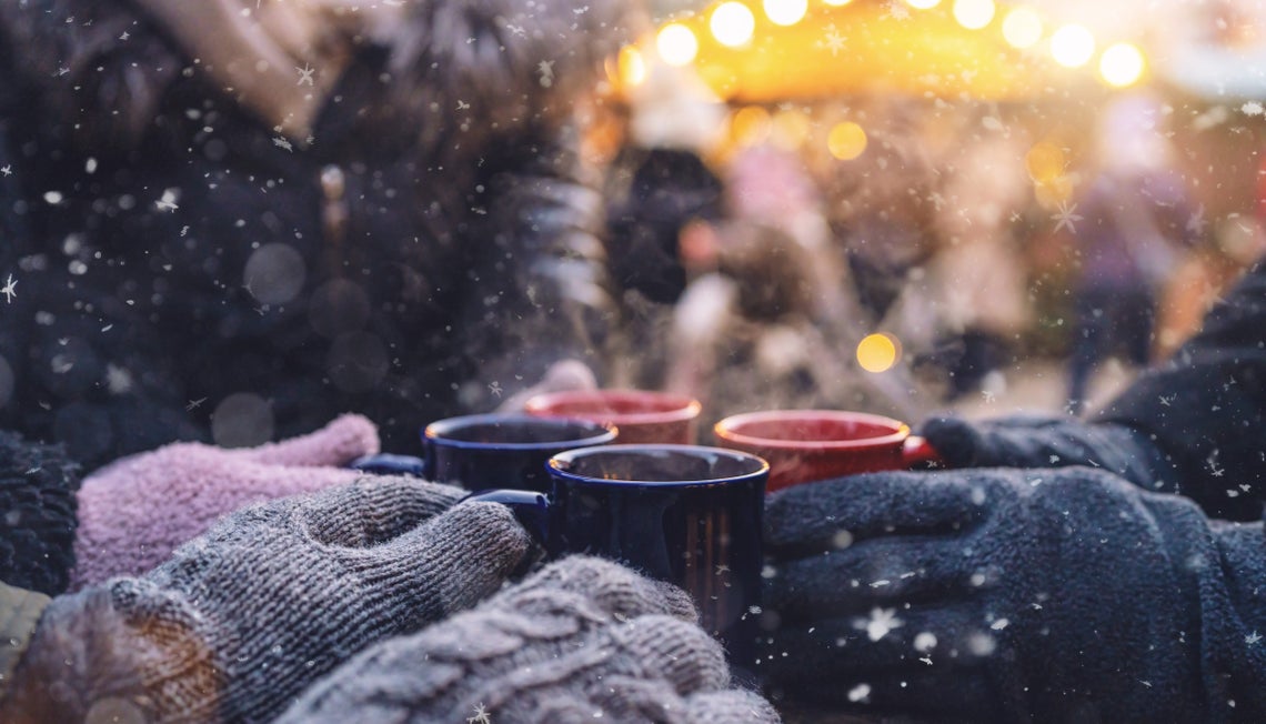 Skupina lidí držící hrníčky na adventním trhu