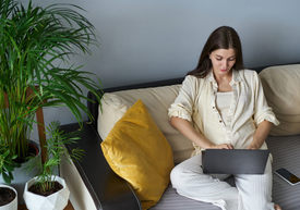 Egy nő ül egy kanapén egy laptopot használva