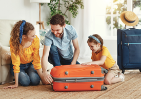 Muž a žena s dieťaťom sa pozerajú na oranžový kufor