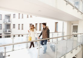 Muž a žena sa držia za ruky a prechádzajú sa po balkóne