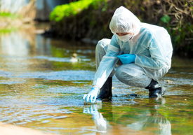 Osoba v bielom obleku a rukaviciach v potoku