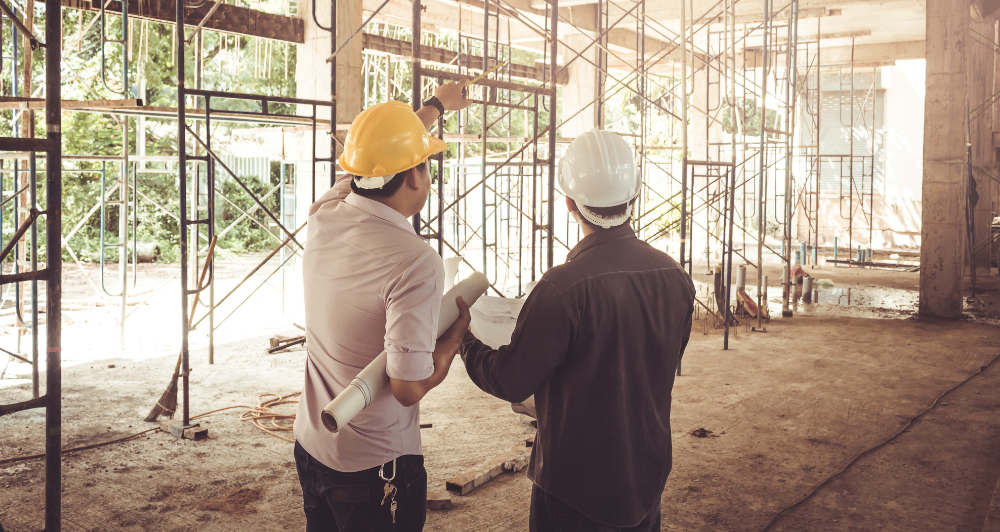 Muž v tvrdom klobúku ukazuje na plán