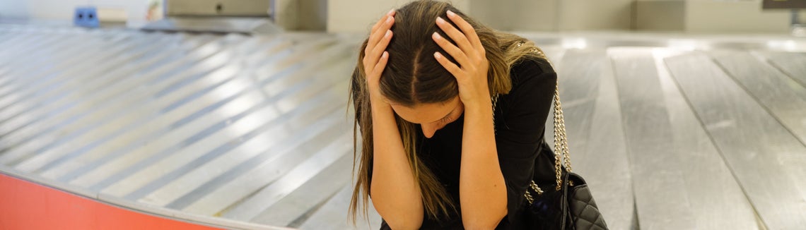 Отчаяна жена седи на празна багажна лента на летище - явно е със загубен багаж и без покритие за това към застраховката си 