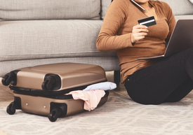 Egy nő ül a földön egy bőrönddel és egy hitelkártyával.